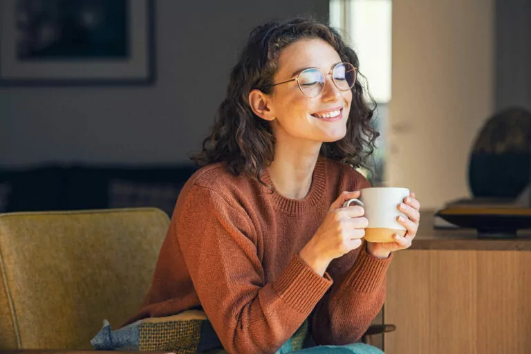 Woman smiling, holding cup of coffee